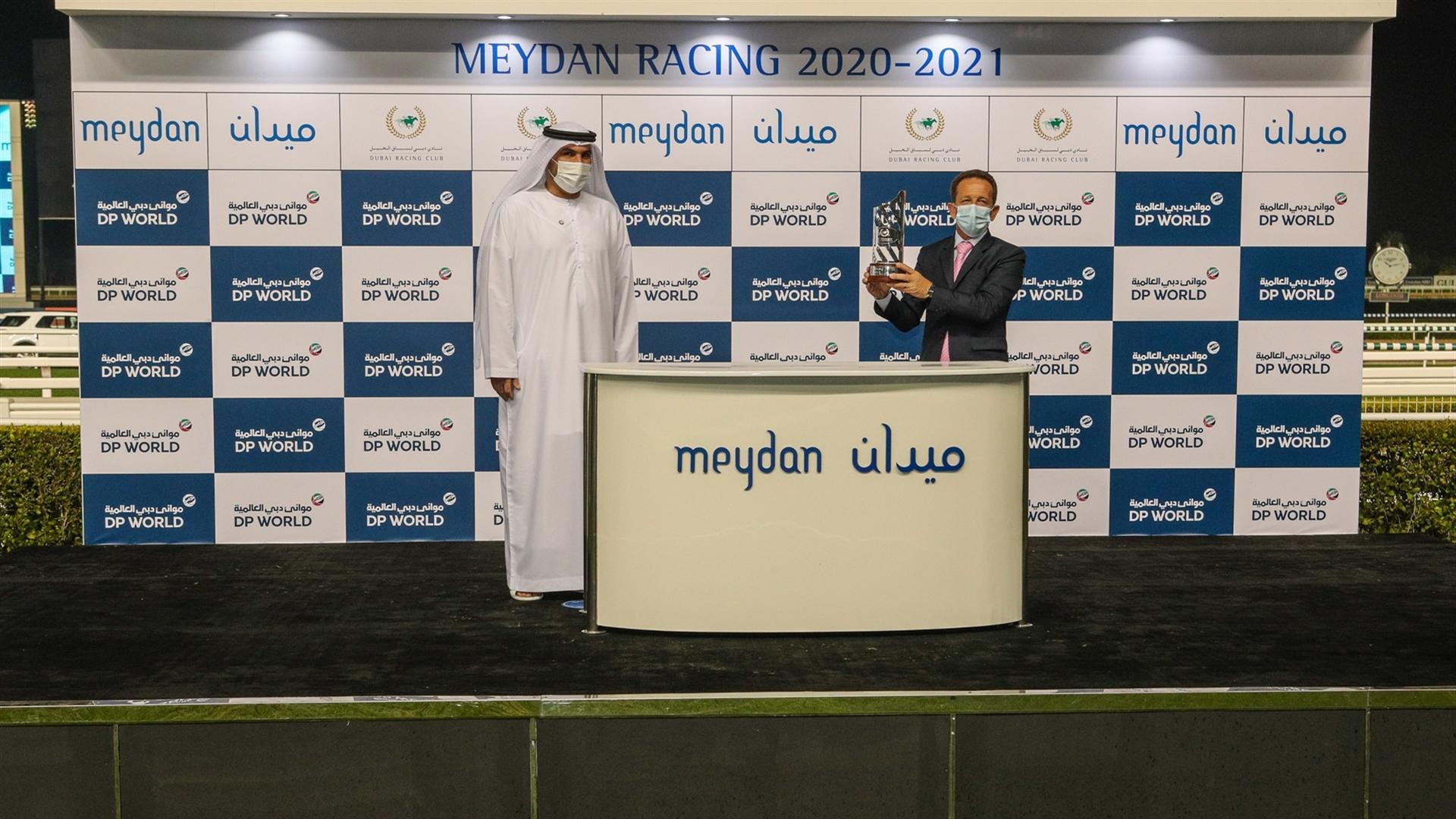 Claude Piccioni accepts the trophy for the Mina Rashid 1400m, Handicap, from Mr. Ayoub Al Mulla, Chief Operating Officer - World Security, on January 14, 2021. (Credit: Dubai Racing Club)