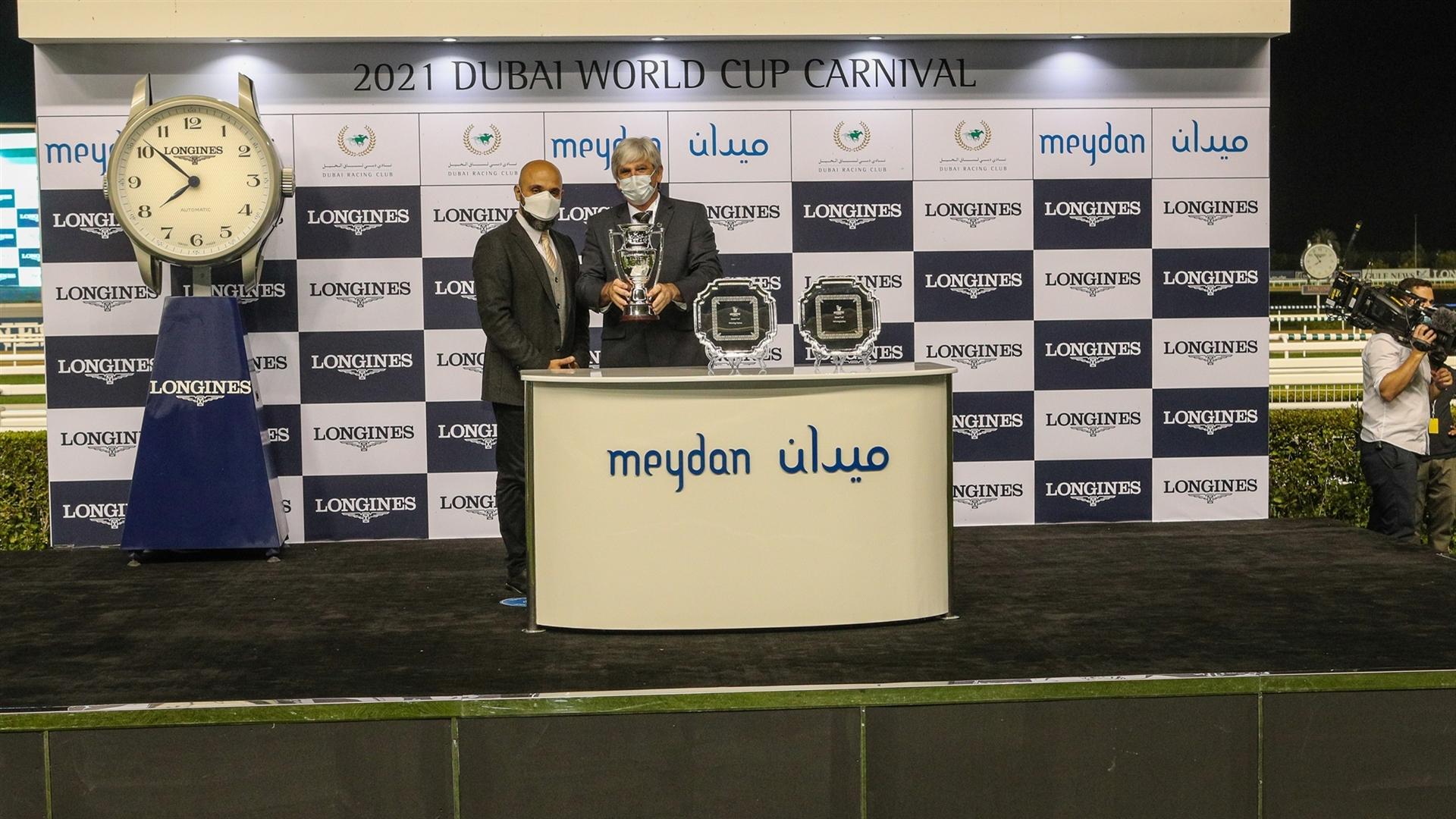 Derek Poupard accepts the trophy for the Zabeel Turf Presented By Longines from Mr. Patrick Aoun, Regional Brand Manager Longines, on January 28, 2021. (Credit: Dubai Racing Club)