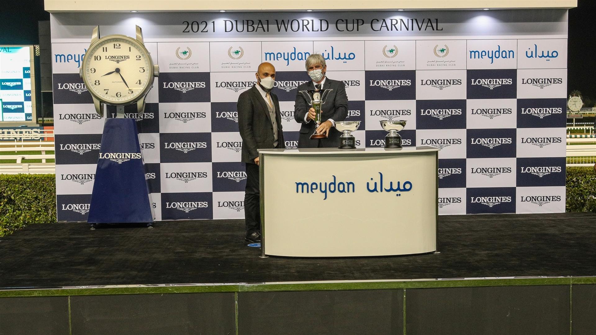 Derek Poupard accepts the trophy for the 1600m, Cape Verde Presented by Longines, from Mr. Patrick Aoun, Regional Brand Manager Longines on January 28, 2021. (Credit: Dubai Racing Club)