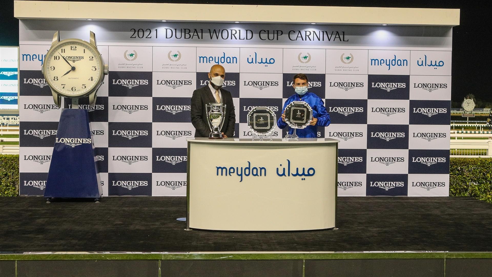 Winning Jockey Mickael Barzalona accepts the trophy for the Zabeel Turf Presented By Longines from Mr. Patrick Aoun, Regional Brand Manager Longines, on January 28, 2021. (Credit: Dubai Racing Club)