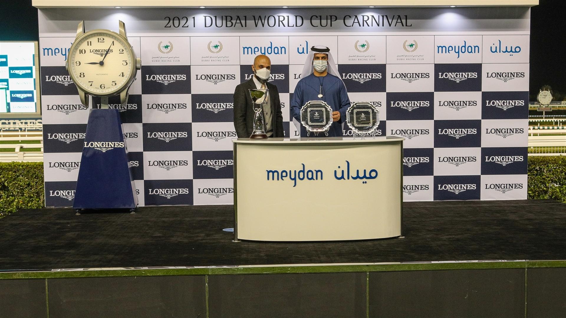 Saeed bin Suroor accepts the trophy for the UAE 1000 Guineas Presented by Longines, from Mr. Patrick Aoun, Regional Brand Manager Longines, on January 28, 2021. (Credit: Dubai Racing Club)