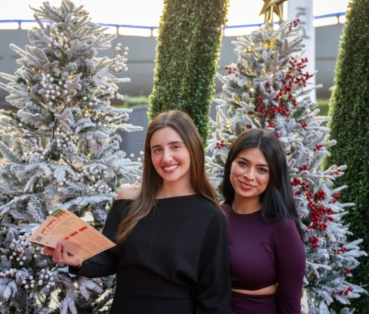 Friends posing by festive Christmas trees