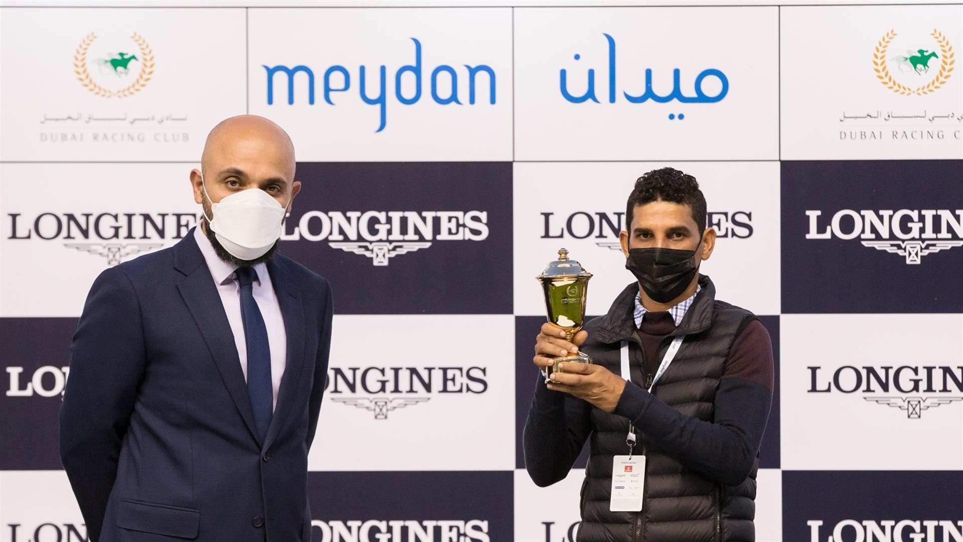 Hussain Abdulla accepts the trophy for the Longines Spirit Collection Turf, 1400m maiden race, from Mr. Patrick Aoun, Regional Brand Manager, on February 13, 2021. (Credit: DRC // Erika Rasmussen)