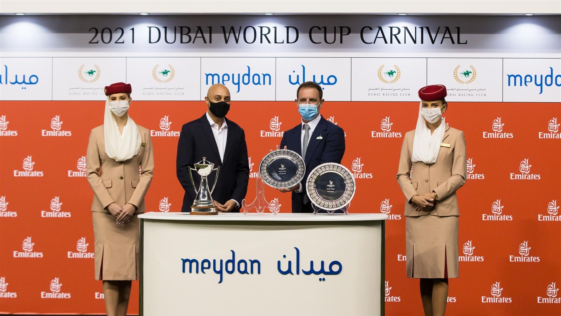 Charlie Appleby accepts the trophy for the Meydan Trophy Sponsored By Emirates Holidays, from Bob Kabli - Senior VP Online Sales Development on February 11, 2021. (Credit: Erika Rasmussen//DRC)
