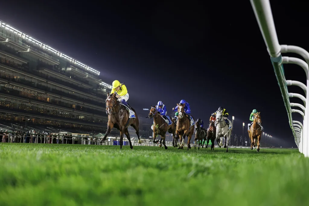 Horses racing at night event.