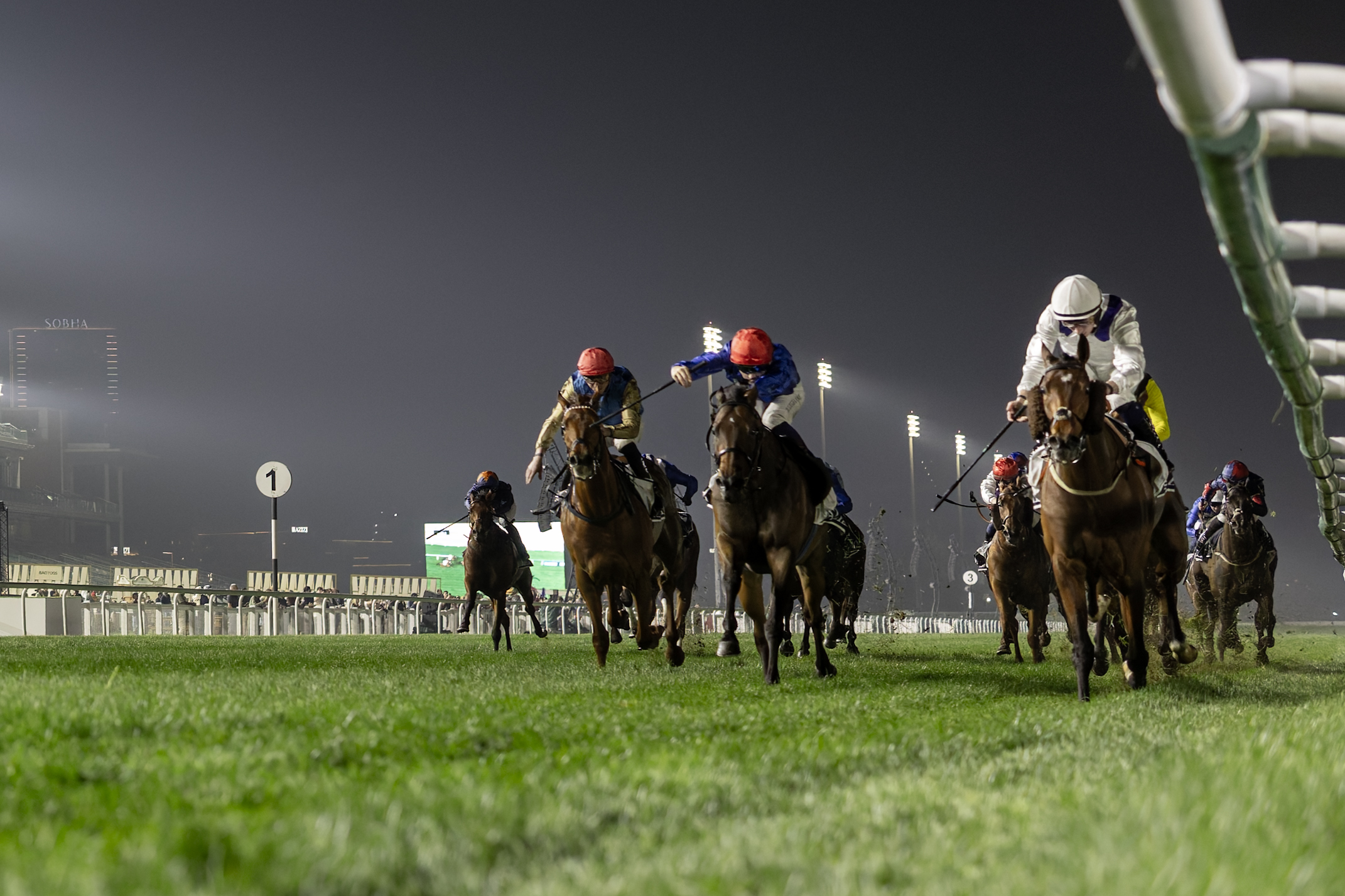Horses racing at night event.