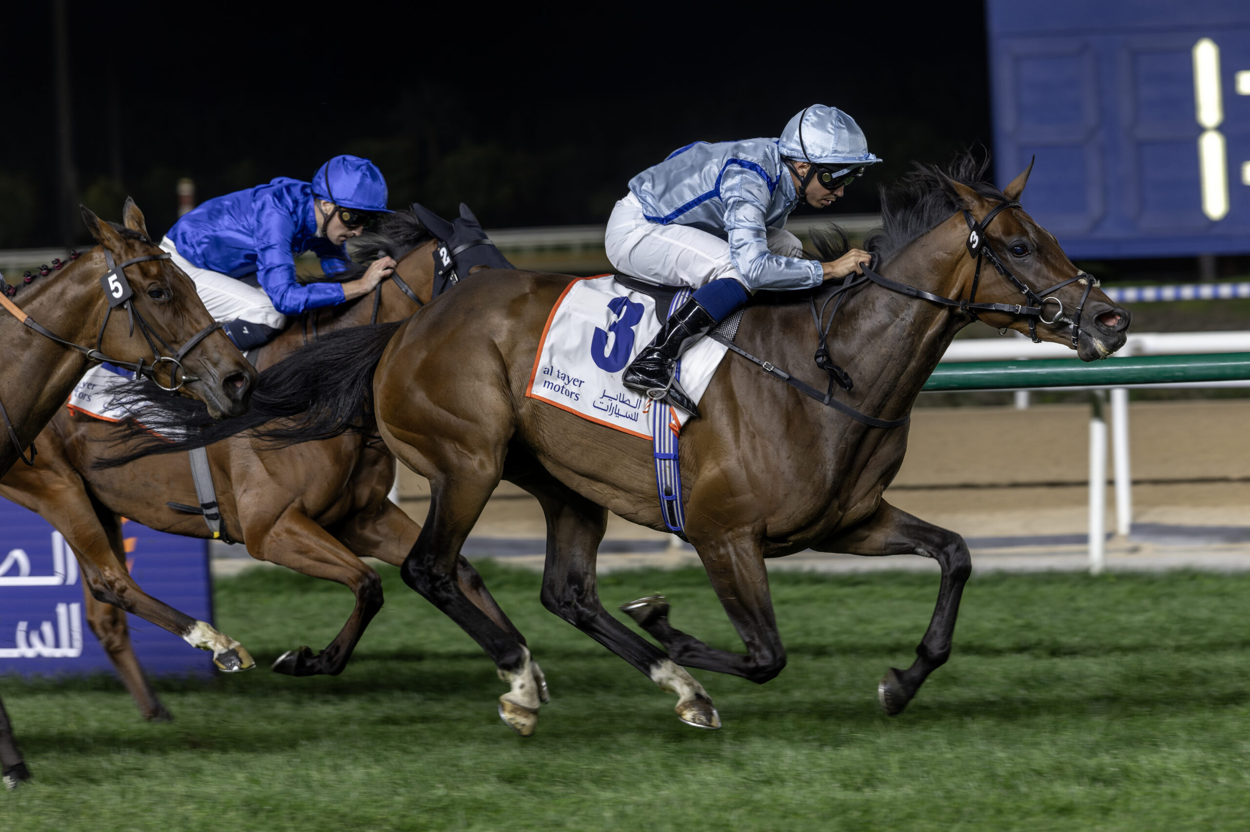 Horses racing under night lights.