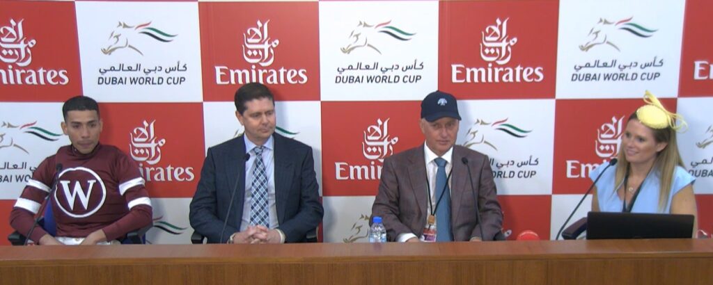 Post-race interview at Dubai World Cup with jockey, trainer, and owners at the press conference.